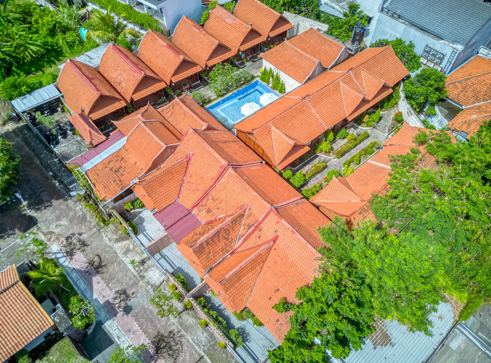 Aerial view of red-tiled villa roofs and tropical gardens